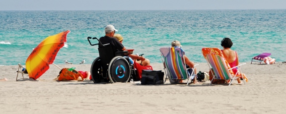 Photo of family including person in a wheelchair on the beach