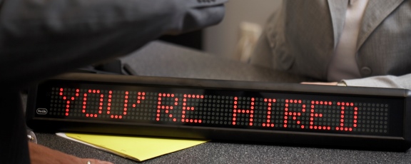 man and woman shaking hands over you're hired LED Sign in office